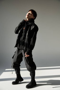 Yakışıklı genç adam moda anlayışını şehir kıyafetleri içinde kendine güvenen bir poz vererek sergiliyor..