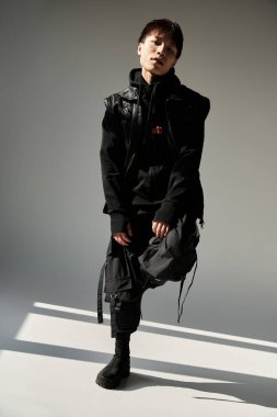 Şık Asyalı adam kendine güvenerek poz veriyor, modern yeteneği sıradan bir havayla karıştırıyor..