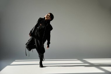 Genç, yakışıklı bir adam modaya uygun kıyafetler giyer ve karizmasını açık bir zemine yansıtır..