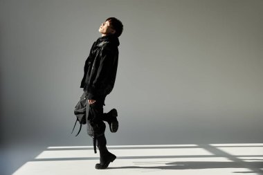 Yakışıklı Asyalı bir adam modern bir stüdyoda zarif bir şekilde duruyor, moda ve güven gösterisi yapıyor..