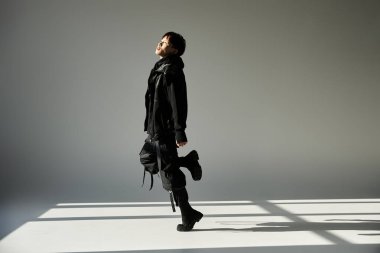 Genç, yakışıklı Asyalı bir adam minimal bir arkaplana karşı şık siyah pozlar veriyor..