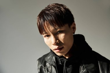 Göz alıcı özellikleri olan genç bir adam şık bir kıyafetle minimalist bir ortamda göze çarpıyor..