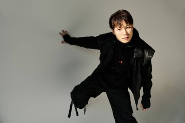 Şık giyinen yakışıklı genç adam, minimalist bir arkaplana karşı anlamlı bir poz verdi..