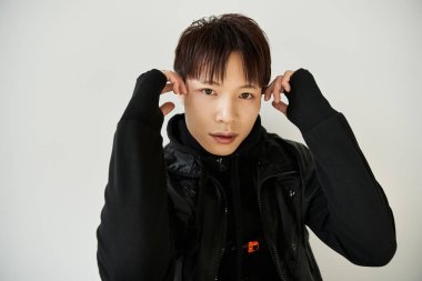 Yakışıklı bir Asyalı, şık kıyafetini basit bir arka plana göre ayarlar..