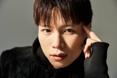 Yakışıklı genç adam düşünceli bir ifadeyle poz veriyor, şık kıyafetlerini ve karizmasını sergiliyor..