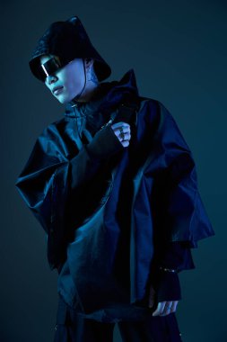 Siyah kıyafetli şık bir genç adam parlak mavi ışığın altında parıldıyor, karizma saçıyor..