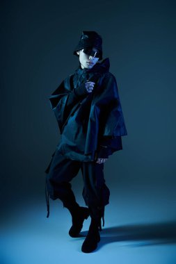 Modaya uygun genç Asyalı bir adam hüzünlü bir arkaplanda kendine güvenle poz veriyor..