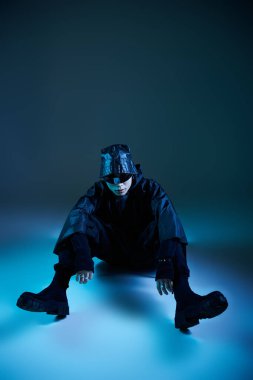 Yakışıklı genç bir adam dikkat çekici bir pozda oturur, eşsiz bir kıyafet ve şık aksesuarlar giyer..