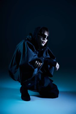 Şık Asyalı adam mavi ışıkta poz veriyor, özgüven yayıyor ve eşsiz bir moda anlayışı var..