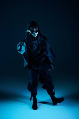 Yakışıklı Asyalı adam çarpıcı mavi bir ortamda kendine has tarzını cesur giysileriyle sergiliyor..