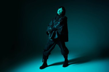 Kendine güveni olan genç bir adam, gösteriş tarzı ve karizmasını cesur mavi bir zemine karşı sergiliyor ve dikkat çekiyor..