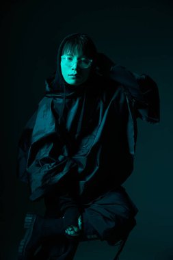 Yakışıklı genç Asyalı bir adam karanlık bir geçmişe karşı poz veriyor, kendine güveni ve tarzı var..