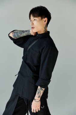 Dövmeleri olan şık, genç bir Asyalı evin içinde rahatça poz veriyor..