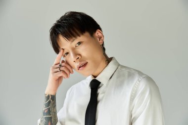 Tarz sahibi genç bir adam, modern bir ortamda derin düşüncelere sahip dövmelerini sergiliyor..