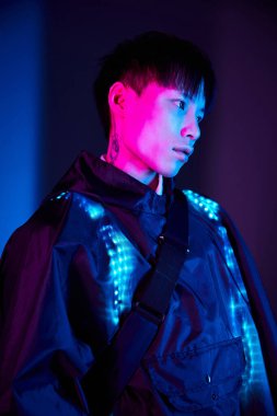 Yakışıklı genç erkek geceleri çarpıcı renklerle aydınlatılmış şık bir kıyafet sergiliyor..