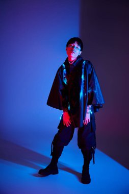 Yakışıklı Asyalı adam renkli ışıklandırma efektlerine karşı modern bir kıyafet sergiliyor..