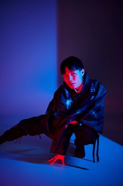 Şık bir Asyalı genç adam cesur bir poz veriyor, kendine güveni ve cazibesi tam..