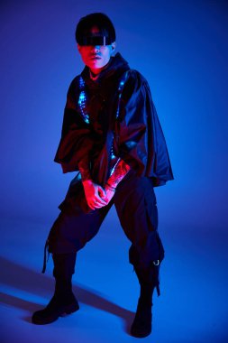 Mavi bir arka planda, şık bir Asyalı kendine güvenen bir poz veriyor, eşsiz modasını sergiliyor.