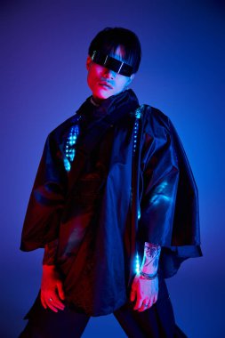 Yakışıklı genç Asyalı bir adam eşsiz moda anlayışını mavi ve kırmızı ışıkların altında sergiliyor..