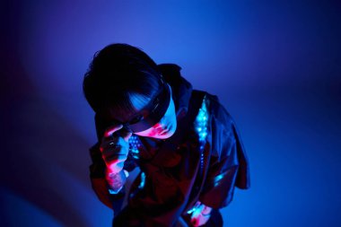 Şık, genç Asyalı adam güneş gözlükleriyle çarpıcı bir şekilde poz veriyor..