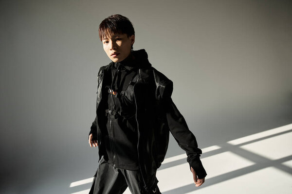 Handsome young man exudes charm while dressed in trendy black attire, basking in natural light.