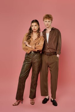 Canlı bir çift şık kıyafetler içinde birlikte durur. Pembe bir zemine karşı aşk ve tarz yayarlar..