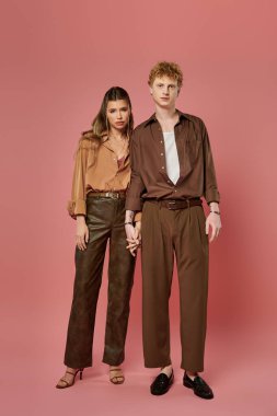 Genç bir çift şık kıyafetler sergiliyor, romantizm ve özgüvenle el ele tutuşuyorlar..