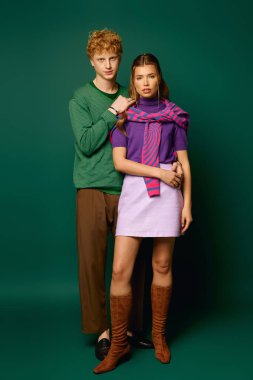 Canlı giysiler içinde neşeli bir çift birbirine yakın duruyor, yemyeşil bir zemin üzerinde aşk yayıyorlar..