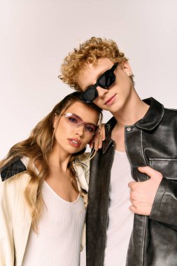 Tarafsız bir arkaplana karşı şık kıyafetler içinde poz verirken sevgi ve tarzla kucaklaşan çift