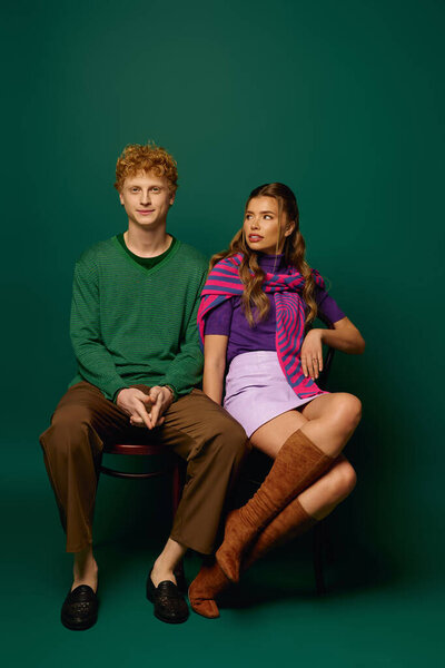 A fashionable young couple sits together, showcasing their love and style in a striking setting.