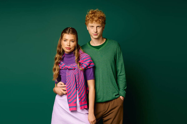 Модная пара стоит рядом, излучая любовь и стиль с яркими, модными нарядами.