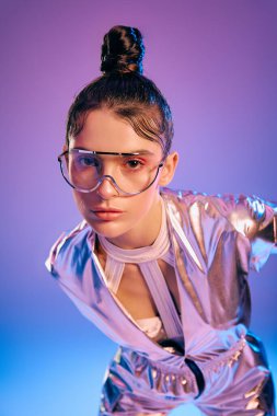 Genç bir kadın gösterişli, holografik fütüristik giysiler içinde kendine güvenerek poz verir..