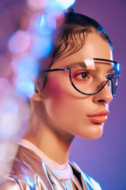 Genç bir kadın çarpıcı bir arkaplana karşı canlı holografik kıyafetlerle benzersiz bir moda sergiliyor..