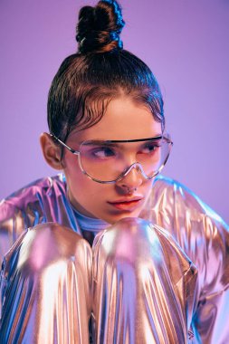 Genç bir kadın cesur holografik kıyafetini canlı ve dinamik bir ortamda sergiliyor..