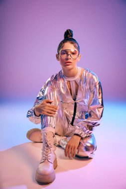 Zarif genç bir kadın, şık holografik kıyafeti ve modaya uygun görünüşü ile modellik yapıyor..