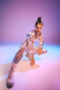 Canlı bir ortamda, şık bir kadın holografik giysiler içinde fütürist bir moda sergiliyor..