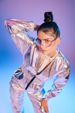 Genç bir kadın modern kıyafetlerini holografik renklerle sergiliyor, kendine güven ve tarz yayıyor..