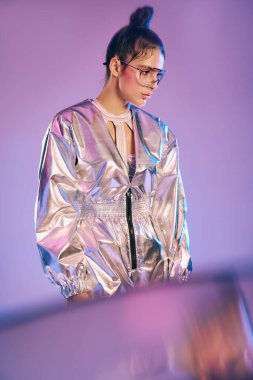 Genç bir kadın, moda holografik kıyafetini sanatsal bir ortamda sergiliyor..