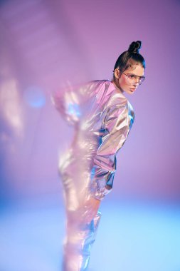 Genç ve güzel bir kadın çarpıcı bir atmosferde modern modayı holografik renklerle sergiliyor..