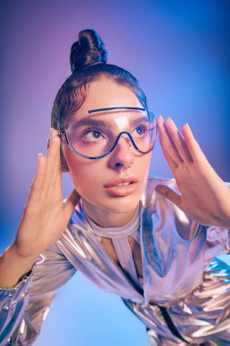 Canlı holografik kıyafetli genç bir kadın renkli ve modern bir ortamda poz veriyor..