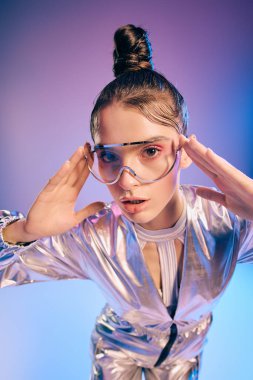 Metalik giyinmiş genç bir kadın, kendine güvenerek holografik tarzının altını çiziyor..