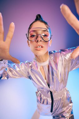 Metalik giyinmiş genç bir kadın, canlı bir arka plana karşı eşsiz tarzını sergiliyor..