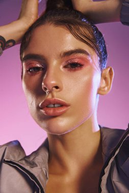 Genç bir kadın, çarpıcı bir holografik arkaplanı olan şık bir kıyafetle modern stili sergiliyor..