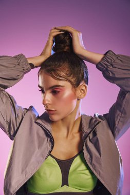 Genç bir kadın, canlı stilini holografik bir arkaplana karşı şık bir kıyafetle gösterir..