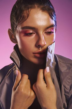 Kendine güvenen genç bir kadın büyüleyici bir holografik arkaplan karşısında modaya uygun şekilde poz veriyor..