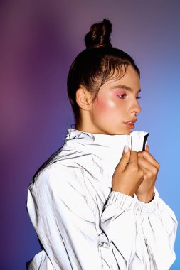 Kadın, modaya uygun kıyafetlerini çarpıcı bir holografik arka plana karşı sergiliyor..