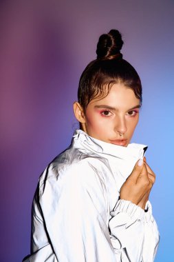 Genç bir kadın, canlı bir holografik arkaplan karşısında şık kıyafetini sergiliyor..