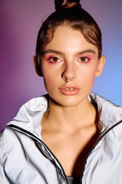 Şık bir kadın, renkli bir holografik arkaplan altında ışıldayan modaya uygun kıyafetlerle kendine güvenir..