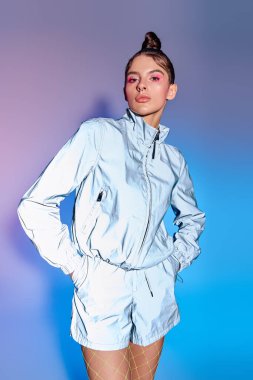 Genç, güzel bir kadın çarpıcı bir holografik arkaplan karşısında şık bir kıyafet modelliyor..