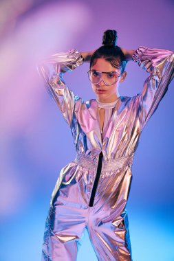 Genç bir kadın holografik bir kıyafetin içinde, canlı renklerle modern stil yayıyor..